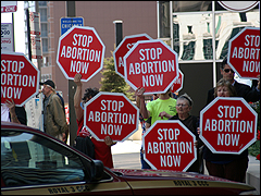 Pro-lifers hold 'Stop Abortion Now' signs as NARAL supporters enter the hotel