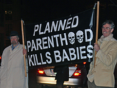 Joe Scheidler and Joseph O'Conner hold a sign reading Planned Parenthood Kills Babies outside the Ritz