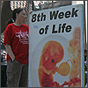 Beth Roland holds an 8th Week of Life sign