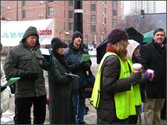 Pro-lifers sing Christmas carols as clinic escorts "protect" thier clients [Photo by Ann Scheidler]