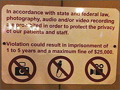 Planned Parenthood's sign is trying to enforce unnamed state and federal statutes against public photography.
