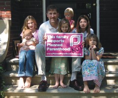 Eric Scheidler and daughters holding a Planned Parenthood yard sign